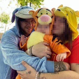 A photo of Ryan Michael Irwin and a woman hugging a baby, taken around Halloween 2024. The wife is dressed as Winnie the Pooh. This baby is dressed as Tigger. Both of their faces have been intentionally redacted. Irwin is dressed as Eeyore.